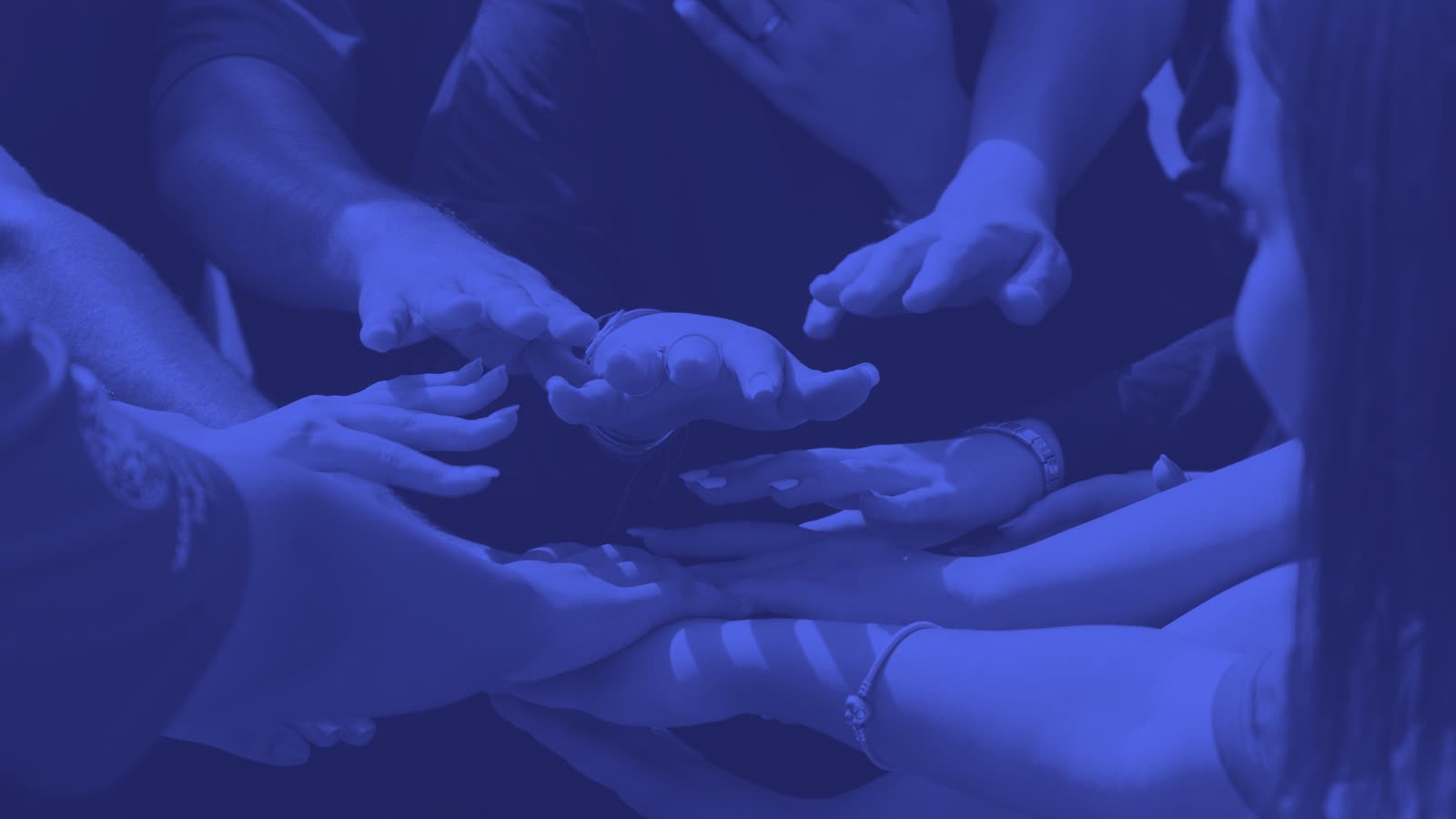 Mehrere Hände übereinander als Symbol für Teamzusammenhalt und interne Kommunikation